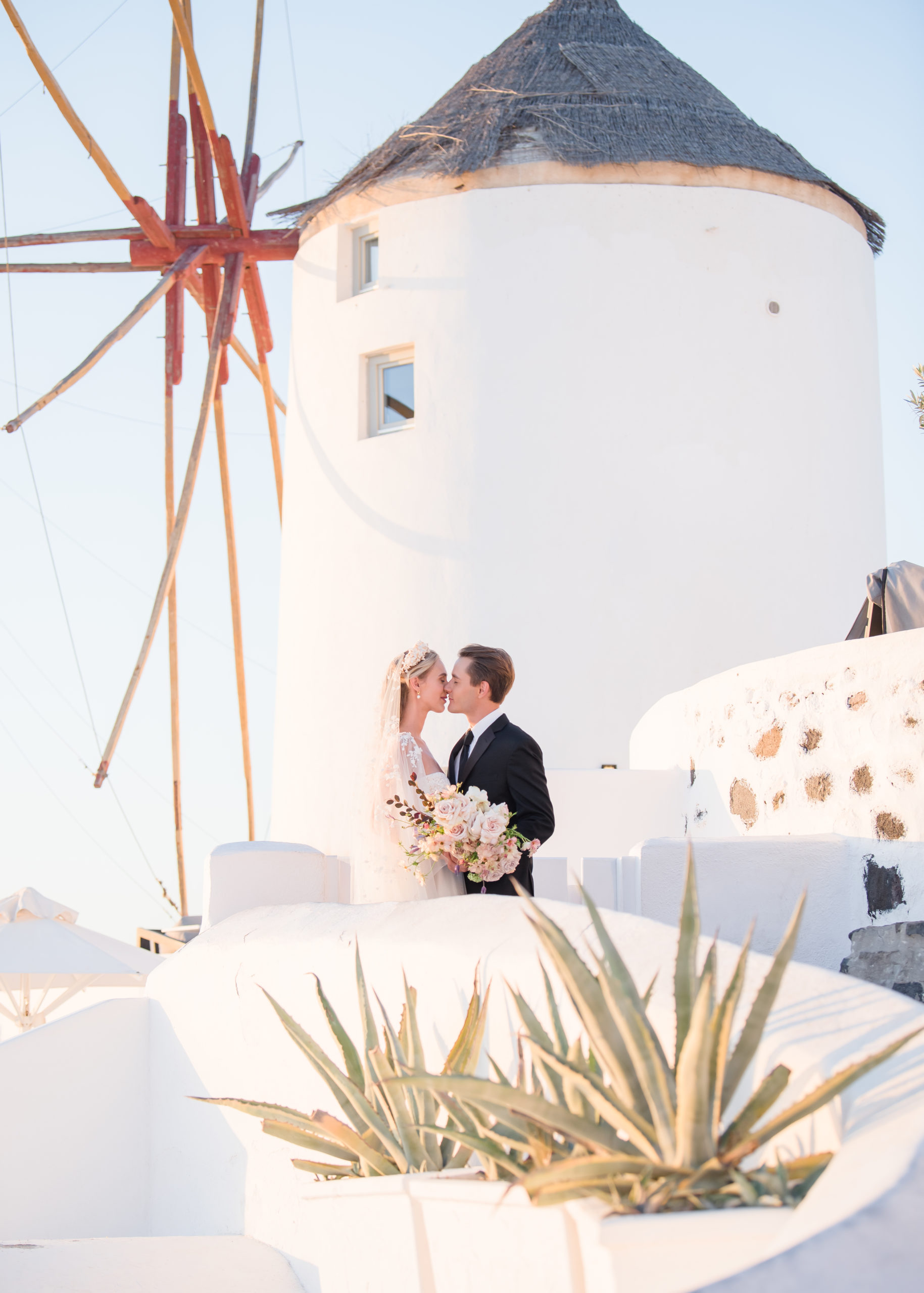 bride and groom kissing in front of windmill