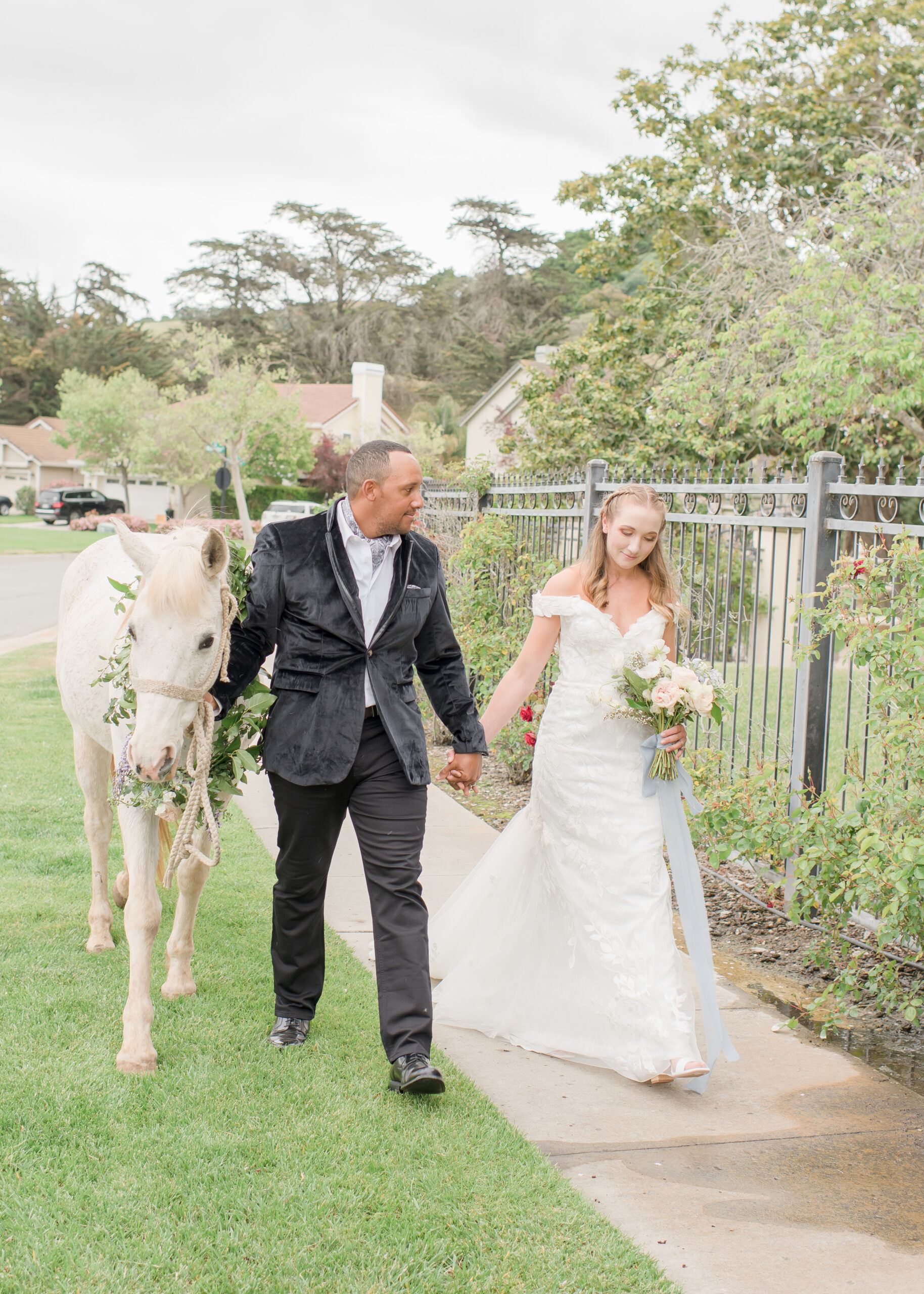 bride and groom walking with white horse