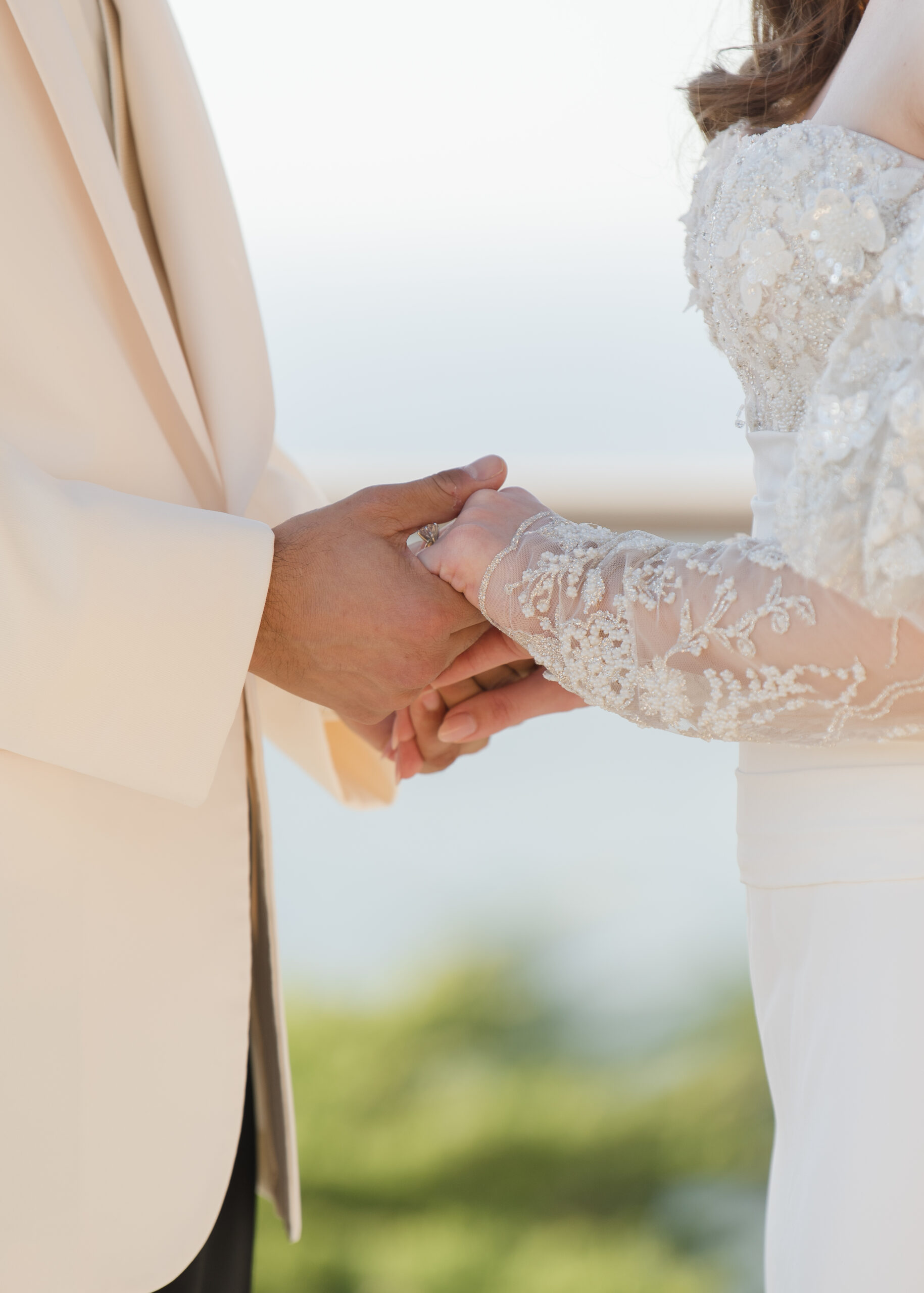 close up of bride and groom holding hands at alter
