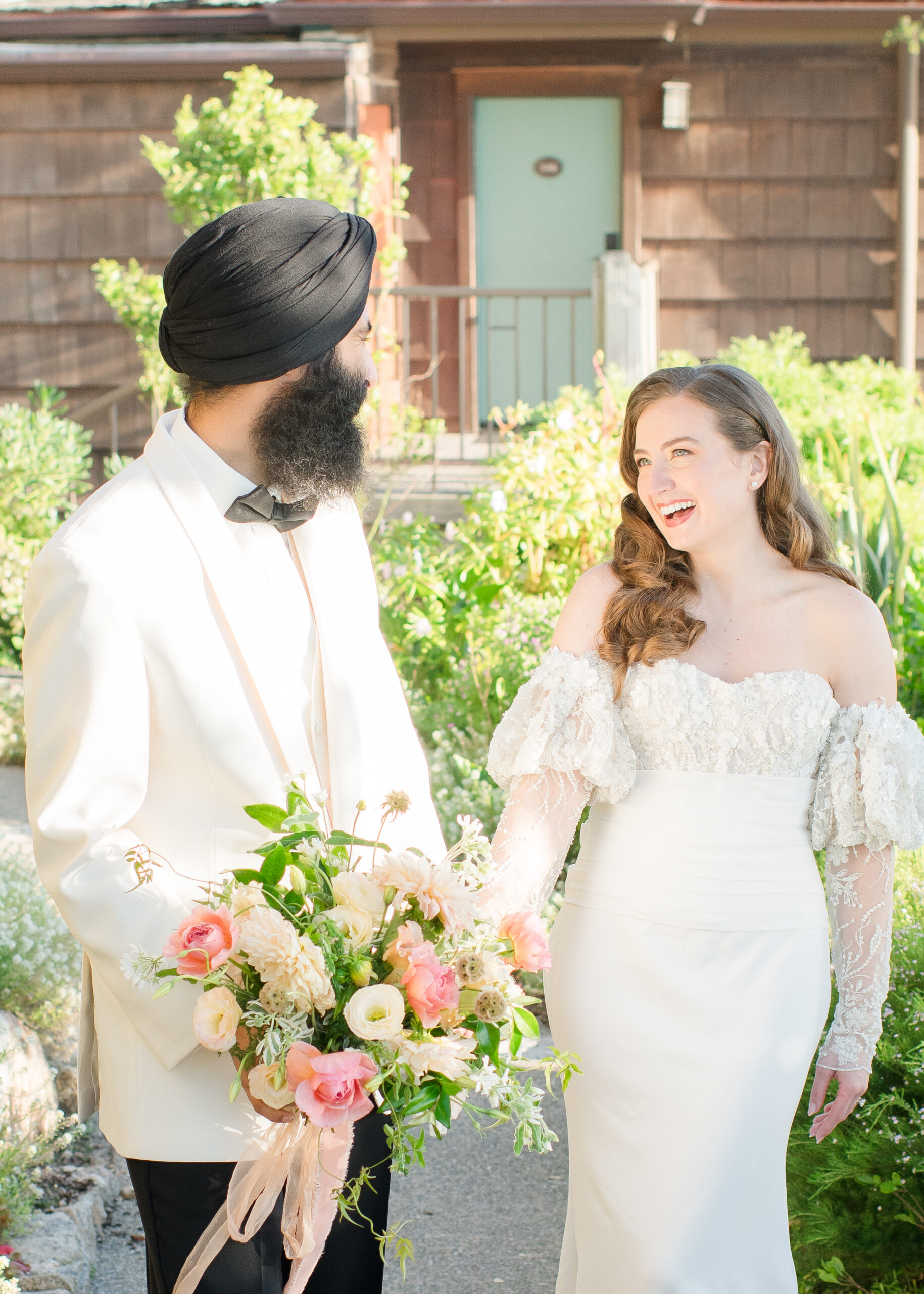 bride and groom holding hands and smiling at each other 