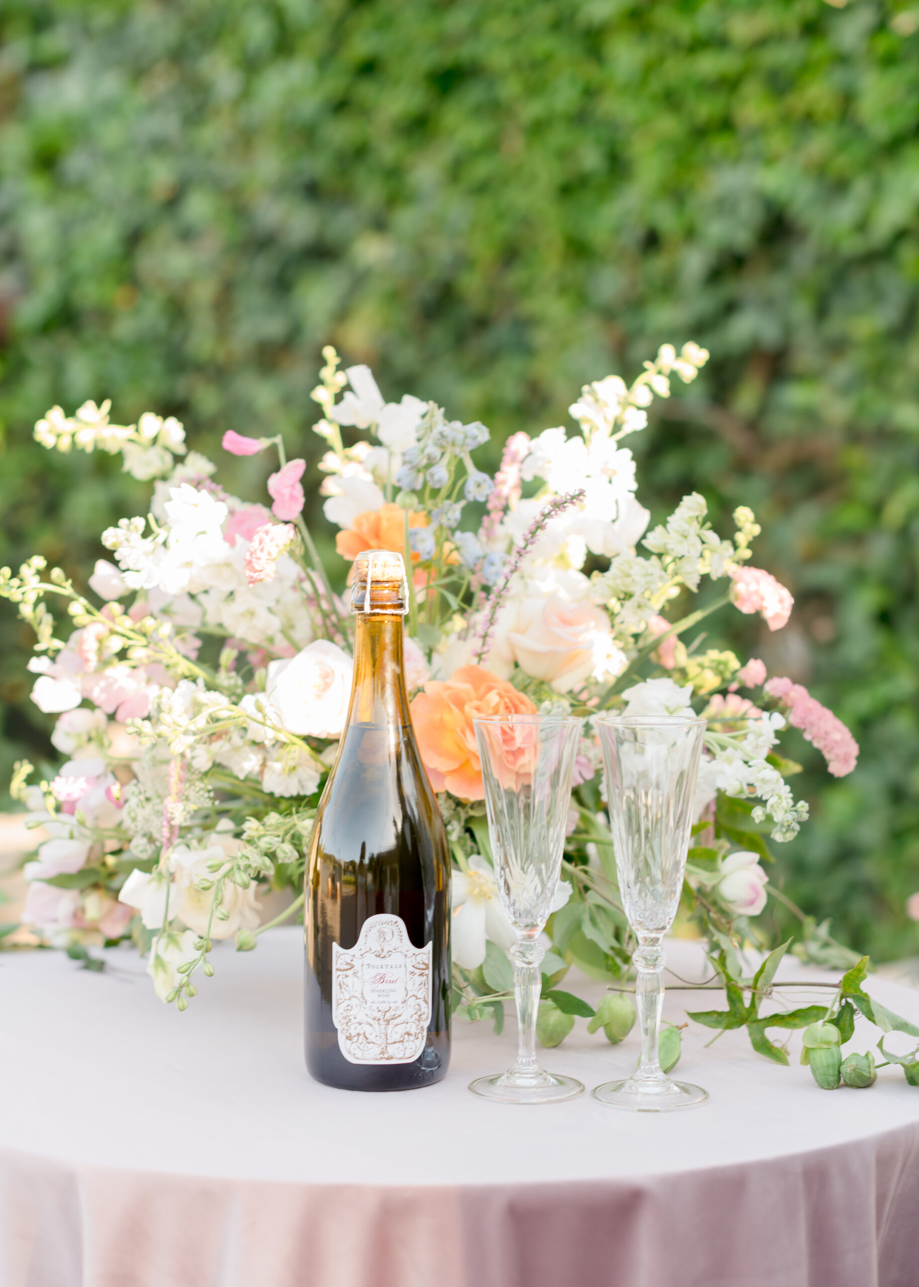 glasses of wine with wine bottle on table with flowers
