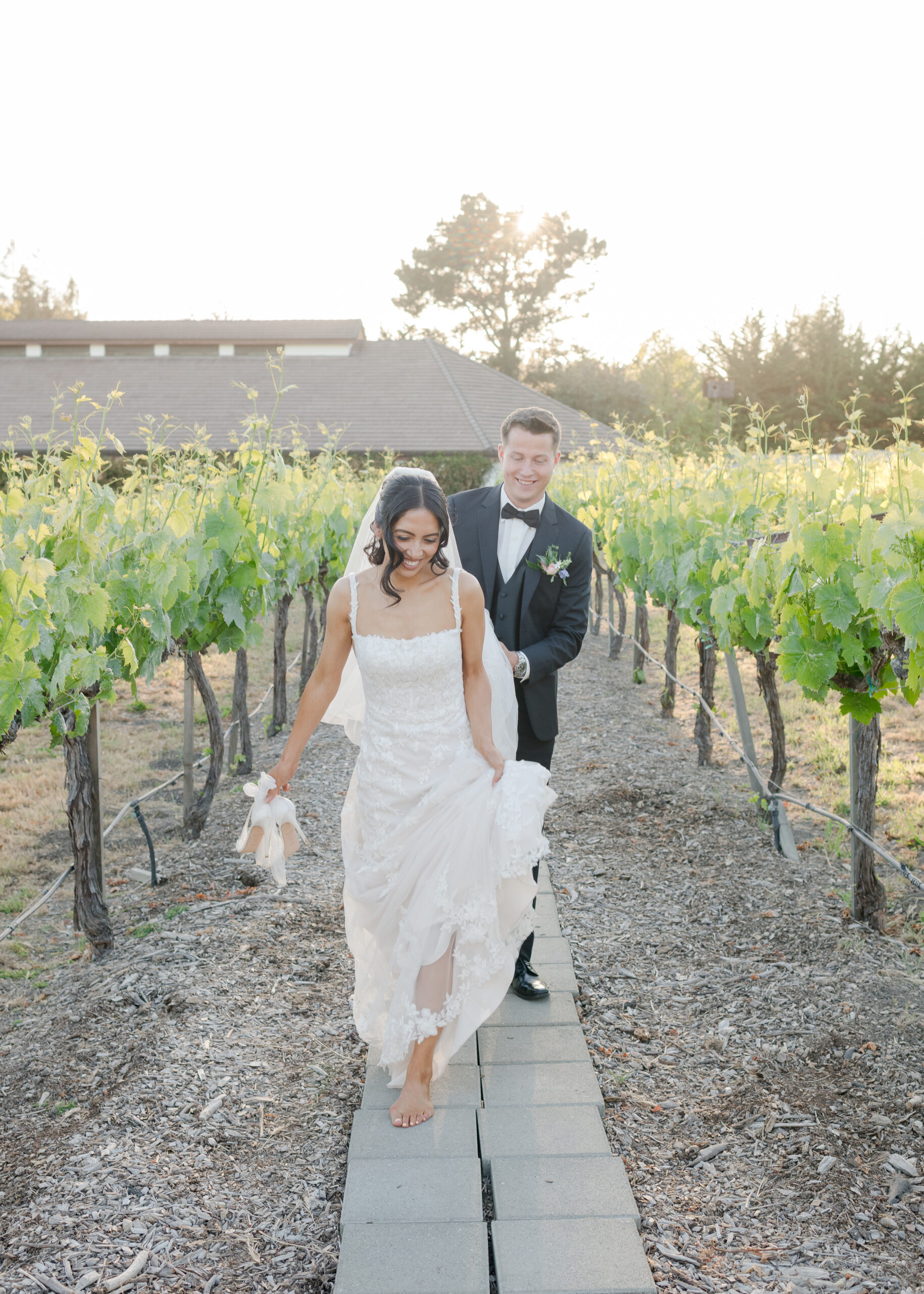 bride walking in front of groom while he holds her dress
